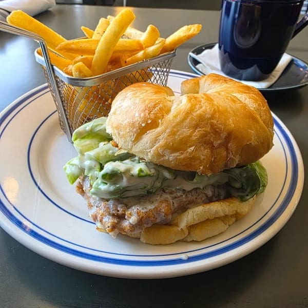 Anchor Allie's fried chicken sandwich with lettuce, sauce, and a side of french fries.