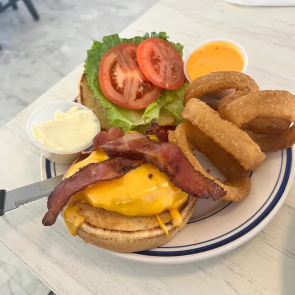Anchor Allie's bacon cheeseburger with lettuce, tomato, onion rings, and dipping sauces.